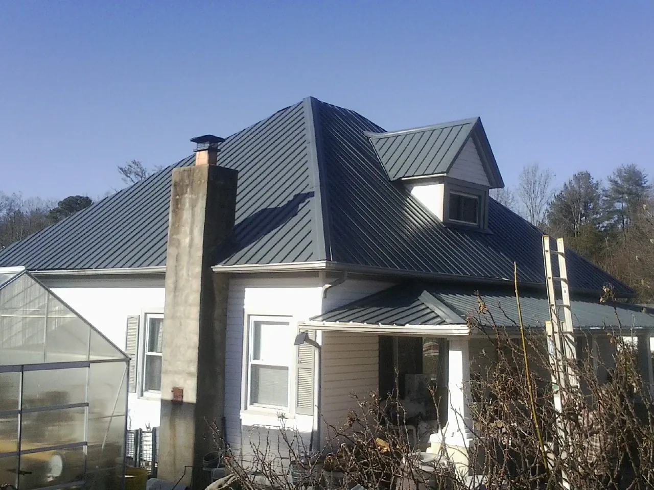 Dark blue standing seam metal roof on a white farmhouse with dormer — Slate & Tile Roof Repair by Roofing Brothers in Albright