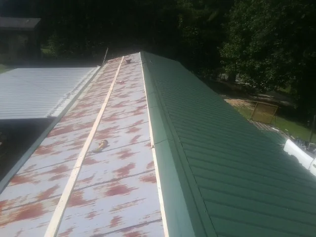 Old rusted panels beside newly installed green metal roofing — Wind Damage Roof Repair by Roofing Brothers in Albright