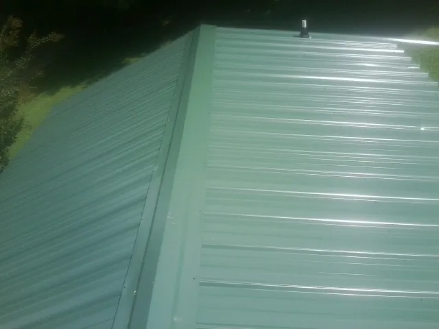 New green metal panels meeting at the ridge of a roof — Flat Roof Repair work by our crew in Albright