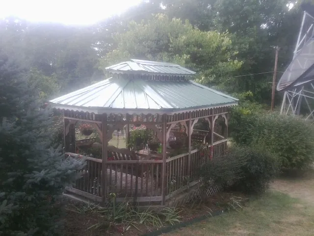 Green metal roof on a backyard gazebo surrounded by garden beds in Albright
