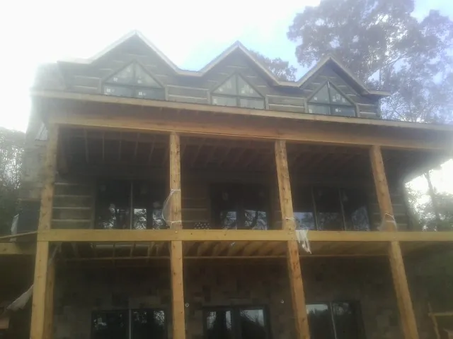 Dormers and porch framing on a large log home under construction — Roof Coating work by our crew in Albright