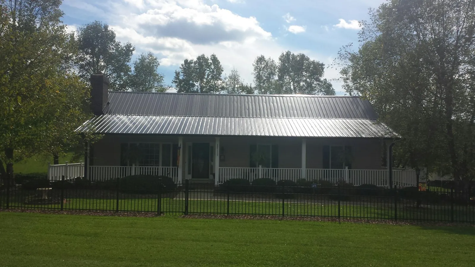 Gray metal roof on a brick ranch with a full width front porch — Gutter Guard Installation work by our crew in Albright