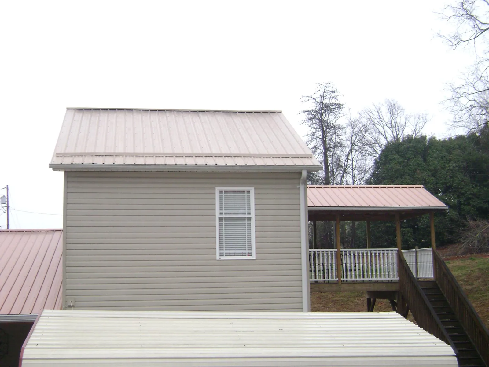 Tan metal roofs on a two story addition and attached porch, from a Roof Replacement job in Albright