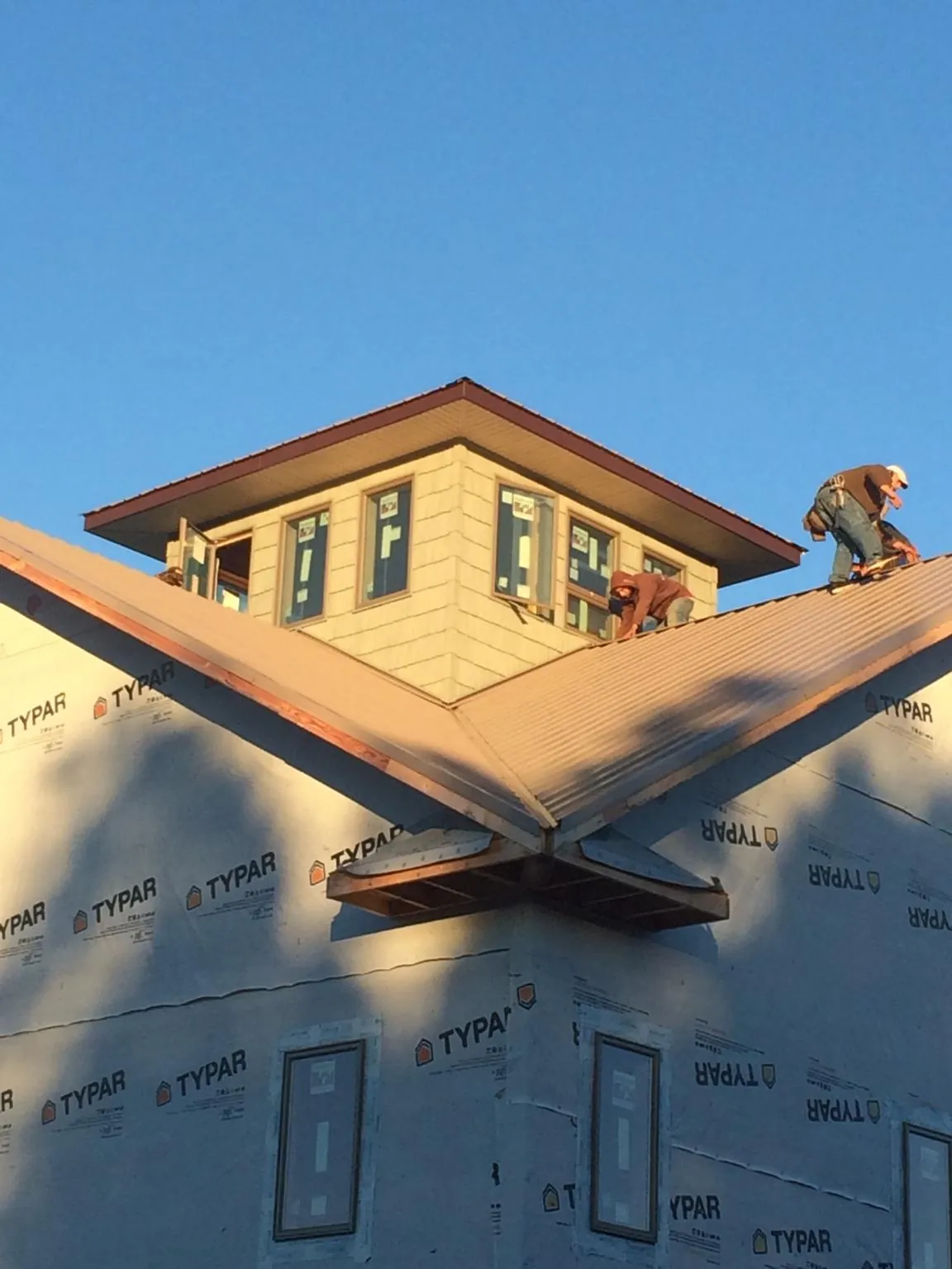 Roofers working around a rooftop cupola on a new metal roof at sunset — Roof Waterproofing in Albright by Roofing Brothers